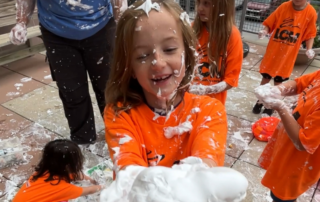 A smiling Lincoln Children's Museum camper holds out a handful of white foam.