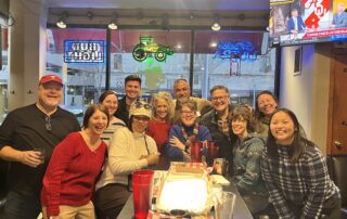 A group of people gathered around a table for a photo at Foundry Happy Hour.